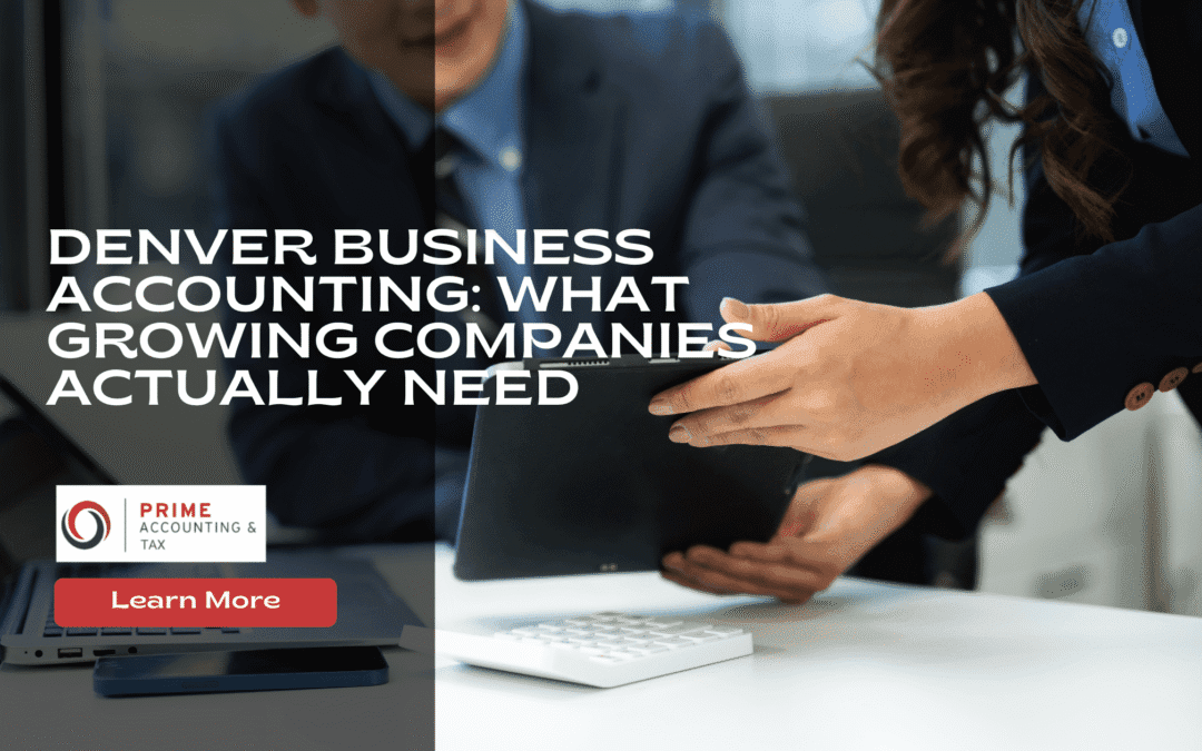 Two people in business attire discuss financial documents at a desk with a tablet and calculator, promoting Denver business accounting services for growing companies.